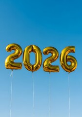 Golden "2026" number balloons floating against a clear blue sky, perfect for New Year celebrations, future concepts, and festive designs.

