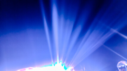 Dramatic white light rays radiate upward from a point source in the center, against a bright and deep electric blue background