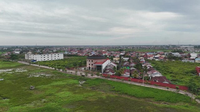 Densely populated residential areas meet rice paddies under a grey tropical sky. A contrast in development.