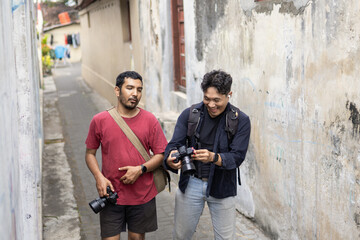 Two photographers walking and reviewing shots in a narrow alley