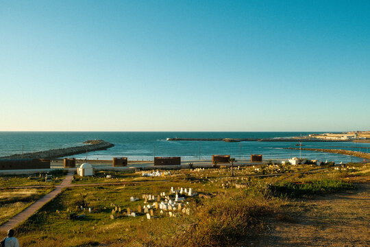 A vast grassy field leads toward the iconic stone water barrier of Rabat-Sal&eacute;, with the Atlantic stretching beyond, capturing a scenic coastal landmark.