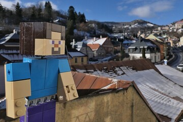 Naklejka premium LEGO Minecraft smiling action figure of main character Steve, enjoying view snow covered roofs in UNESCO mining town of Banska Stiavnica from Zvonova street during sunny winter day. 