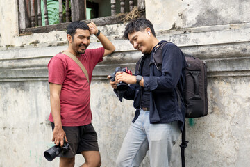 Two Indonesian photographers reviewing images and laughing outdoors