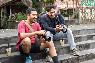 Two Indonesian photographers reviewing images and laughing outdoors