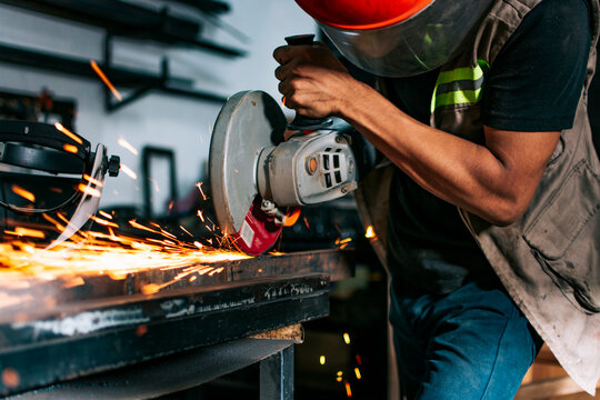 Metalworking professional using an angle grinder in the workshop. Man using a grinder in a workshop
