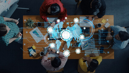 A diverse group of professionals engages in a collaborative business meeting with digital overlays of a world map, symbolizing innovation and strategy development in an office setting. Trope