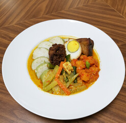 Indonesian meal featuring lontong rice cakes served with coconut vegetable curry, boiled egg, spicy potato sambal and a braised meat portion, authentic Southeast Asian home-style cuisine