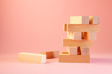 Wooden block tower on pink background, business and risk concept.