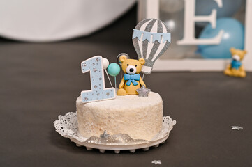 close-up shot of birthday cake with figure of blue bear holding balloon. cake is decorated with number 1. first birthday cake in decorations for celebrating for children.