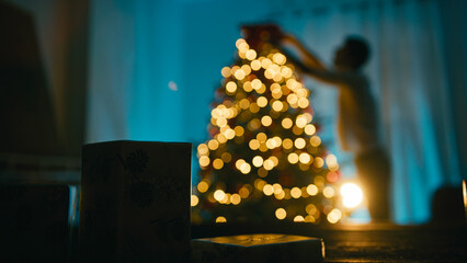 Silhouette of a man decorating the Christmas tree at night
