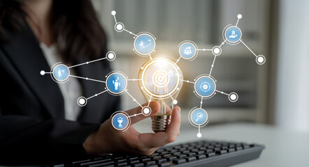 A businesswoman holds a glowing light bulb symbolizing innovation, surrounded by connection icons that illustrate technology and modern work concepts. Crux