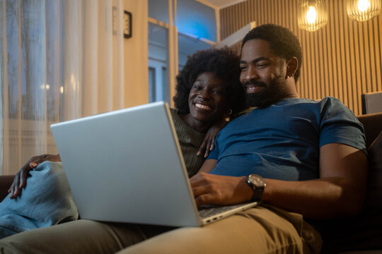 Laptop, living room and couple search website information for home investment, loan or real estate property discussion on sofa.