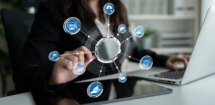 A businesswoman interacts with a digital interface while working on a laptop, representing modern technology and remote connectivity in today workplace. Crux