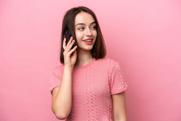 Fototapeta premium Young Ukrainian woman isolated on pink background keeping a conversation with the mobile phone with someone