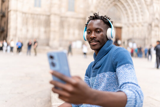 African American man traveling in Barcelona using smartphone and headphones