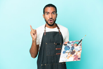 Young artist latin man holding a palette isolated on blue background intending to realizes the...