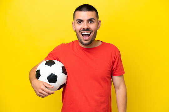 Young caucasian man playing soccer isolated on yellow background with surprise facial expression - Powered by Adobe