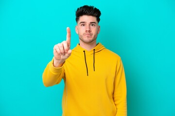 Young caucasian man isolated on blue background counting one with serious expression