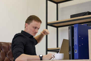 Frustrated office worker clenching fist at desk