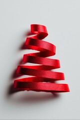 A vibrant red ribbon spirals upward, resembling a Christmas tree, against a clean white background, evoking festive holiday spirit.