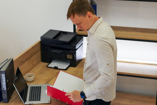 Businessman examining red folder in modern office workspace