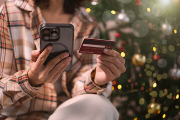 woman using Mobile holiday shopping payment person holding smartphone and credit card to complete secure online transactions during festive Christmas season