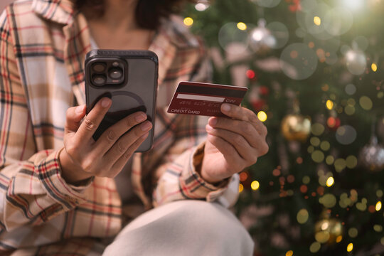 woman using Mobile holiday shopping payment person holding smartphone and credit card to complete secure online transactions during festive Christmas season