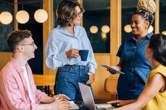 Group of young adults casually discussing ideas in a modern office space