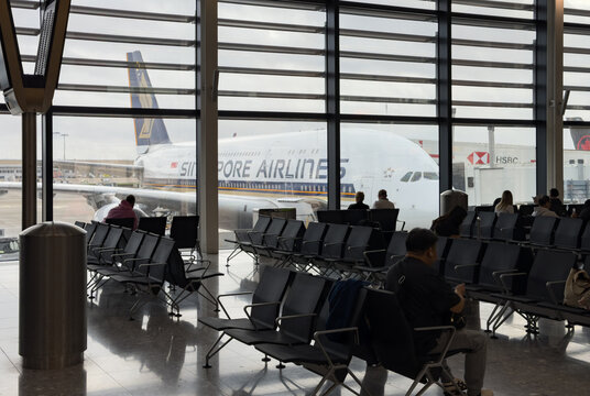 Passengers sit and wait to board Singapore Airlines Airbus A380 at an airport departure gate