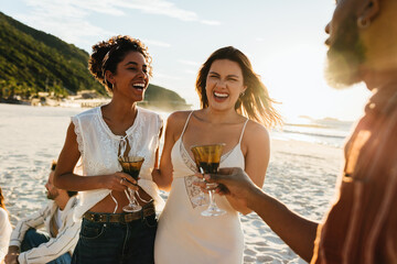 Young adults laughing and socializing on the beach during sunset
