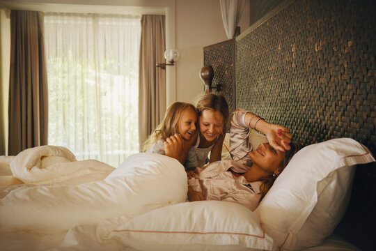 Happy family waking up together in a cozy hotel room bed on a sunny morning