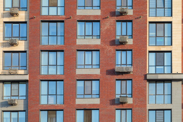 Modern multi-story buildings with beige, red brick, and glass facades, balconies, and windows. Urban architecture concept, front view.