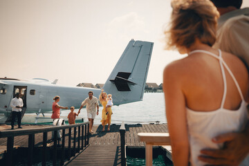 Happy family arriving by airplane at waterside resort, father, mother, and children ready for vacation