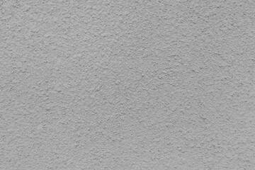 Grey wall with a lot of small holes. The wall is made of concrete and has a rough texture