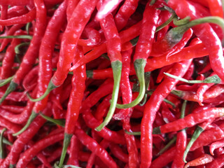A vibrant cascade of fiery red chili peppers, their wrinkled skins and green stems creating a striking contrast. A hot and spicy sight that promises intense flavor and heat.