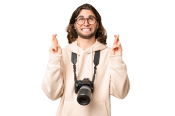 Young photographer man over isolated background with fingers crossing