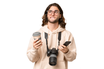 Young photographer man over isolated background holding coffee to take away and a mobile while thinking something