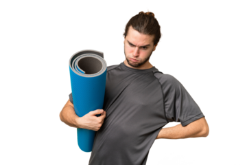 Young sport man going to yoga classes while holding a mat over isolated background suffering from backache for having made an effort