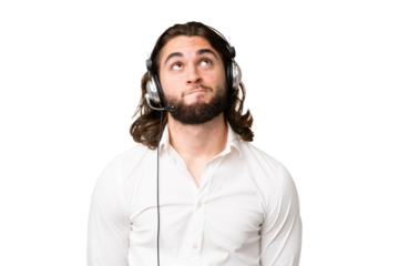 Telemarketer man working with a headset over isolated chroma key background and looking up