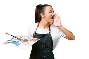 Obraz premium Young artist woman holding a palette over isolated chroma key background shouting with mouth wide open to the side