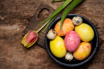 Colorful tulips and painted Easter eggs on a wooden table