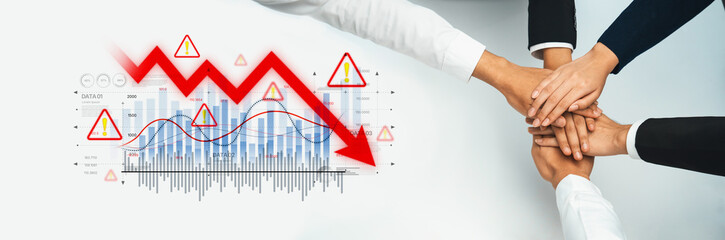 A diverse team unites their hands in a gesture of collaboration over financial graphs indicating...