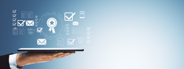 Businessman hand holding digital tablet with user interface icons of certification, checklists, and communication on light blue gradient background.