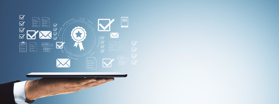 Businessman hand holding digital tablet with user interface icons of certification, checklists, and communication on light blue gradient background.