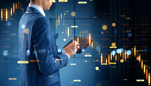 Business trader analyzing stock market data on tablet with digital candlestick chart and numbers overlay in modern financial office background.