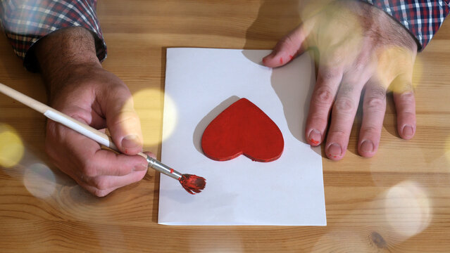 Man painting red heart decoration, symbol for love and romance