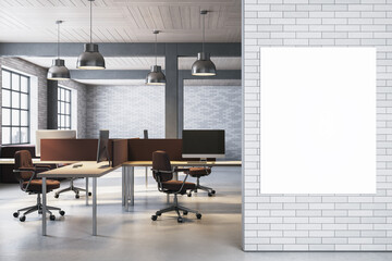 Vertical blank poster mockup on modern white brick wall in open-plan office interior with desks, screens, and pendant lighting. 3D Rendering