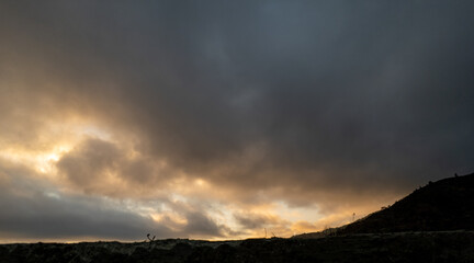 Dark dramatic sky with glowing clouds over silhouette landscape