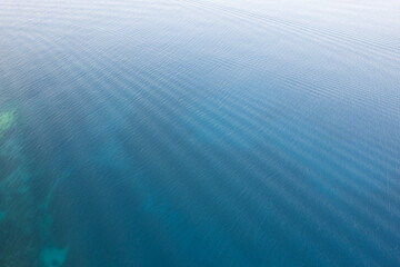 Drone aerial of Tranquil blue water reflecting sunlight with gentle ripples in a peaceful setting