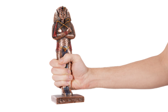 A person's hand grasping a wooden figurine, a statue of a human figure
